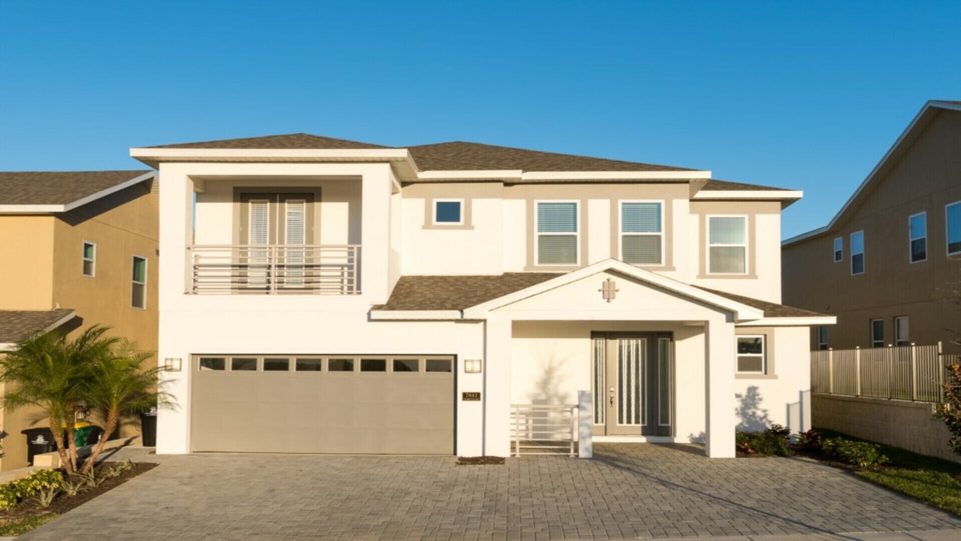 A two-story residential building with a garage, a balcony, and a small porch.
