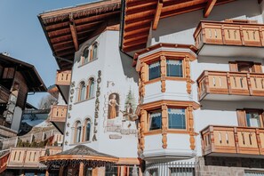 A traditional building with a corner turret, multiple windows, and a balcony with wooden railings. - Hotel La Soldanella (Moena)