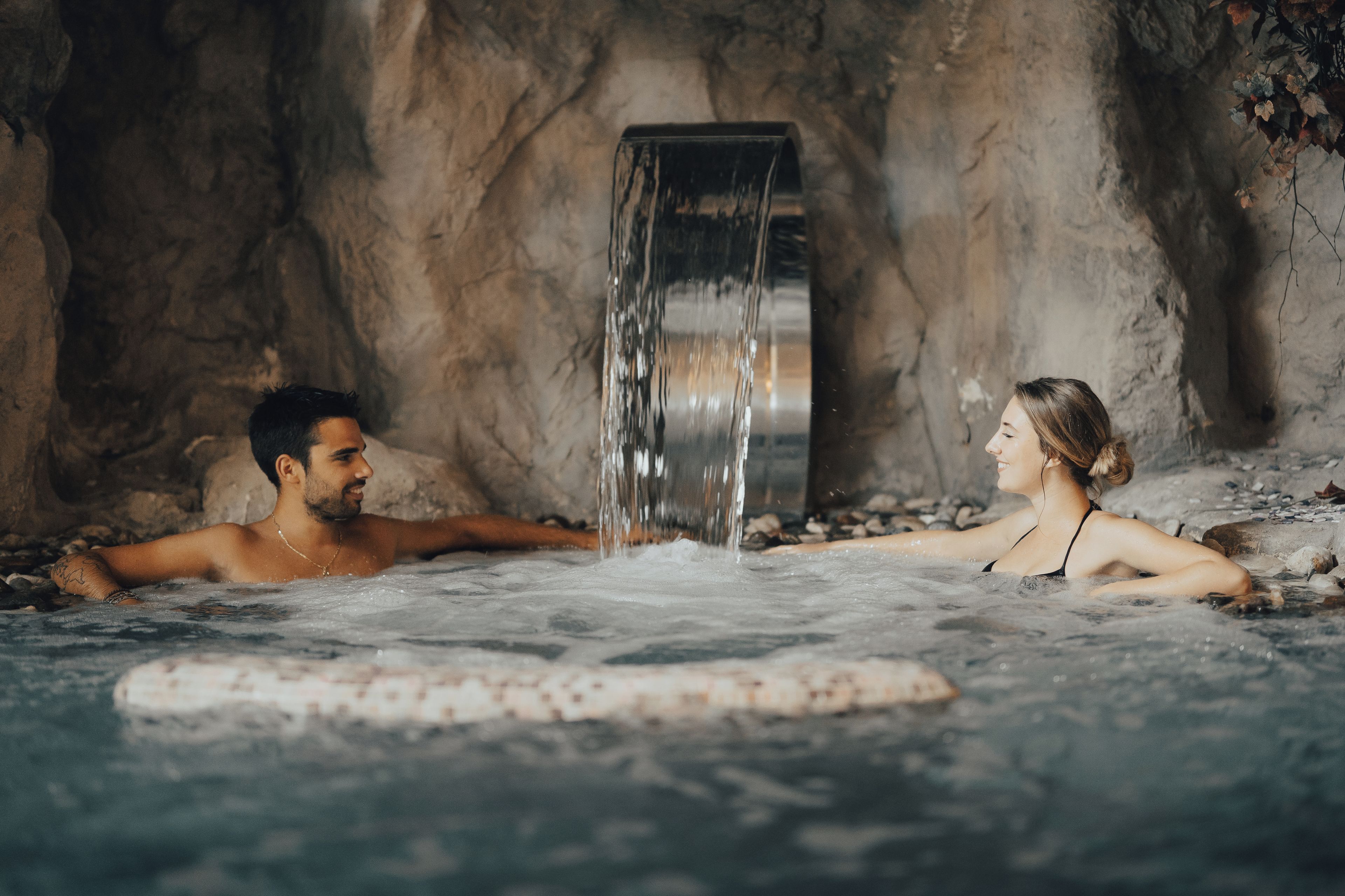 Um casal em uma águas termais com cachoeira.