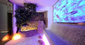A room with a stone wall, a moss-covered rock, and a tiled floor.