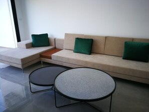 A modern living room with a beige sofa, two round tables, and green cushions. - Dar Chadilia (Nabeul)