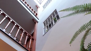 A multi-level interior with a balcony, large windows, and indoor plants. - Pensión Doña Trinidad (Seville)