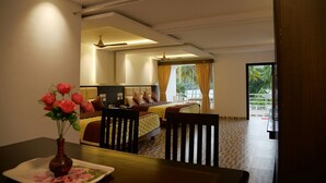 Habitación de hotel con cama, escritorio, silla, un jarrón con flores y vistas al exterior.