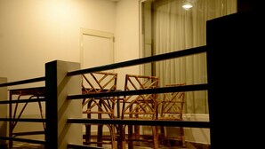 Una habitación con sillas de madera, una puerta y una ventana con cortinas.