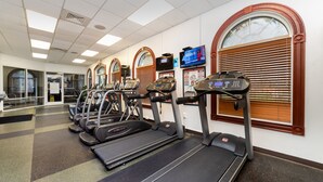 Ett gym med flera löpband, motionscyklar och en tv-skärm som visar en nyhetskanal.