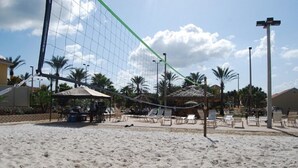 En strandvolleybollplan med nät, palmer och strandstolar.