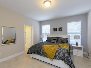 A bedroom with a bed, bedside tables, a mirror, and a door.