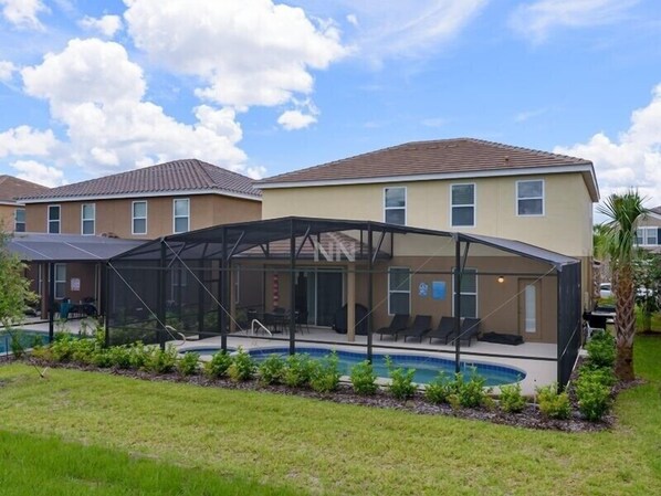 A residential property with a covered outdoor swimming pool, a lawn, and a neighboring house.