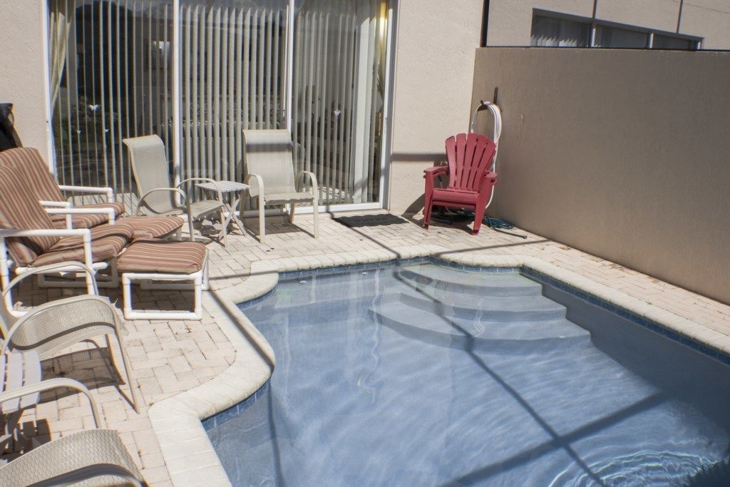Un área de piscina con sillones de playa y una silla roja.