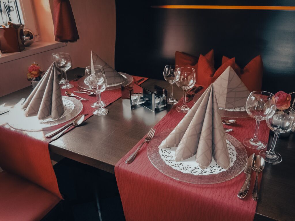 A dining table set with red napkins, wine glasses, and cutlery.