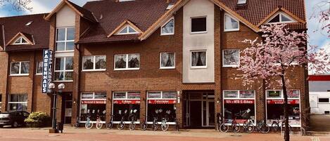 A multi-story building with commercial storefronts on the ground floor, including a bike shop and a service center.