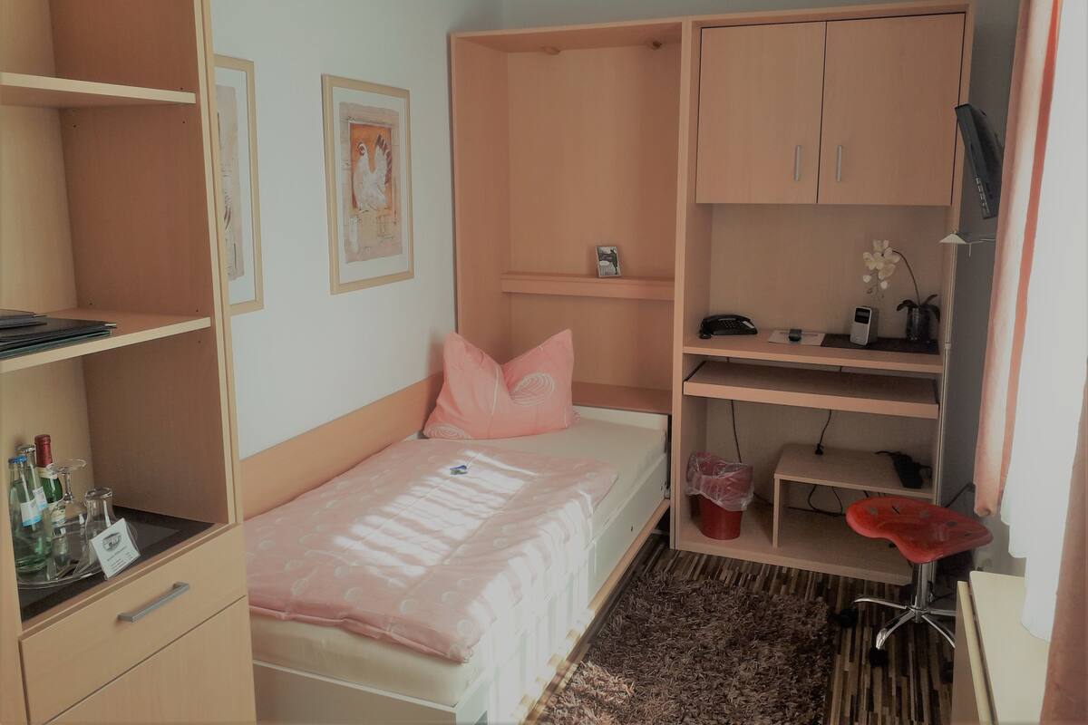 Un dormitorio con cama, escritorio, silla y armario.