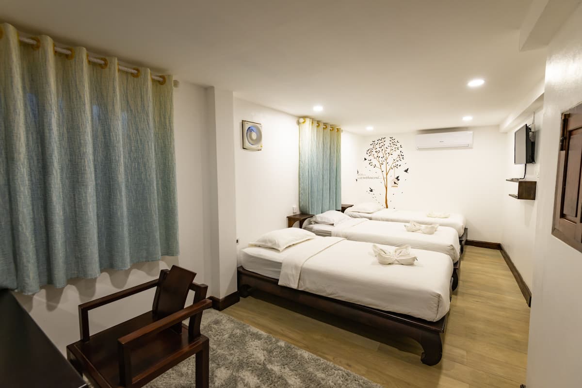 A hotel room with two beds, a desk, and a chair.