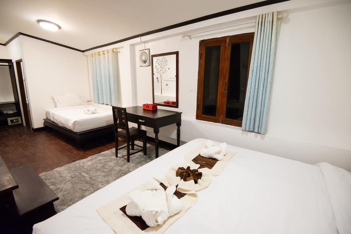 A hotel room with two beds, a desk, and a chair.