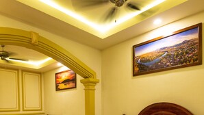 A room with a ceiling fan, a framed painting of a landscape, and a decorative archway.