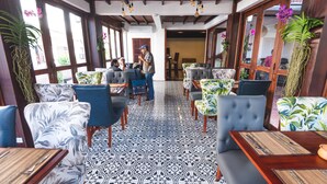 A restaurant with patterned floor tiles, blue and white upholstered chairs, and wooden tables.