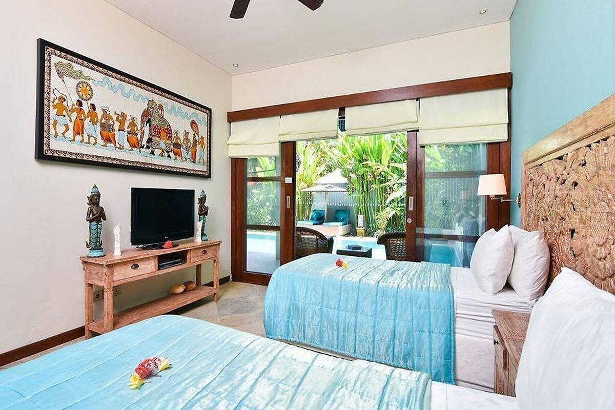 A hotel room with two beds, a television, a painting, and a view of the outdoors.
