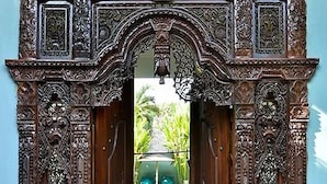 An ornate wooden doorway leading to a pool area. - Bali Mystique Apartment (Keroboken Kelod)