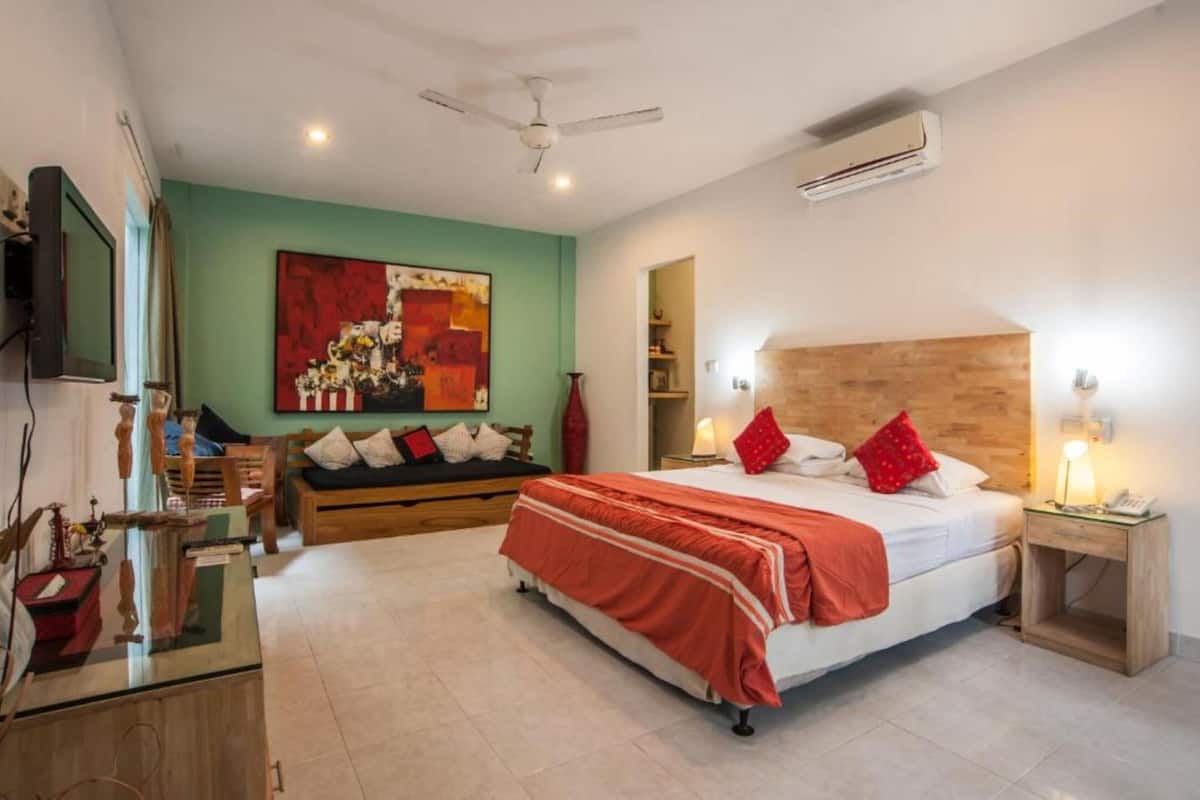 A bedroom with a bed, bedside table, nightstand, and a ceiling fan.