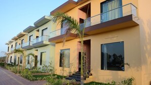 A row of modern, multi-story residential buildings with balconies, a paved driveway, and well-maintained landscaping.