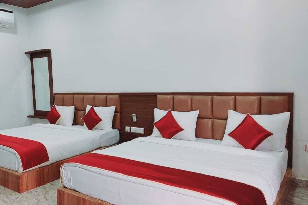 Une chambre d’hôtel avec deux lits, chacun recouvert d’une courtepointe rouge et blanche, et dotée d’une tête de lit en bois.