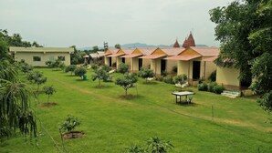 A row of brick buildings with red-tiled roofs, a grassy courtyard, and small trees.