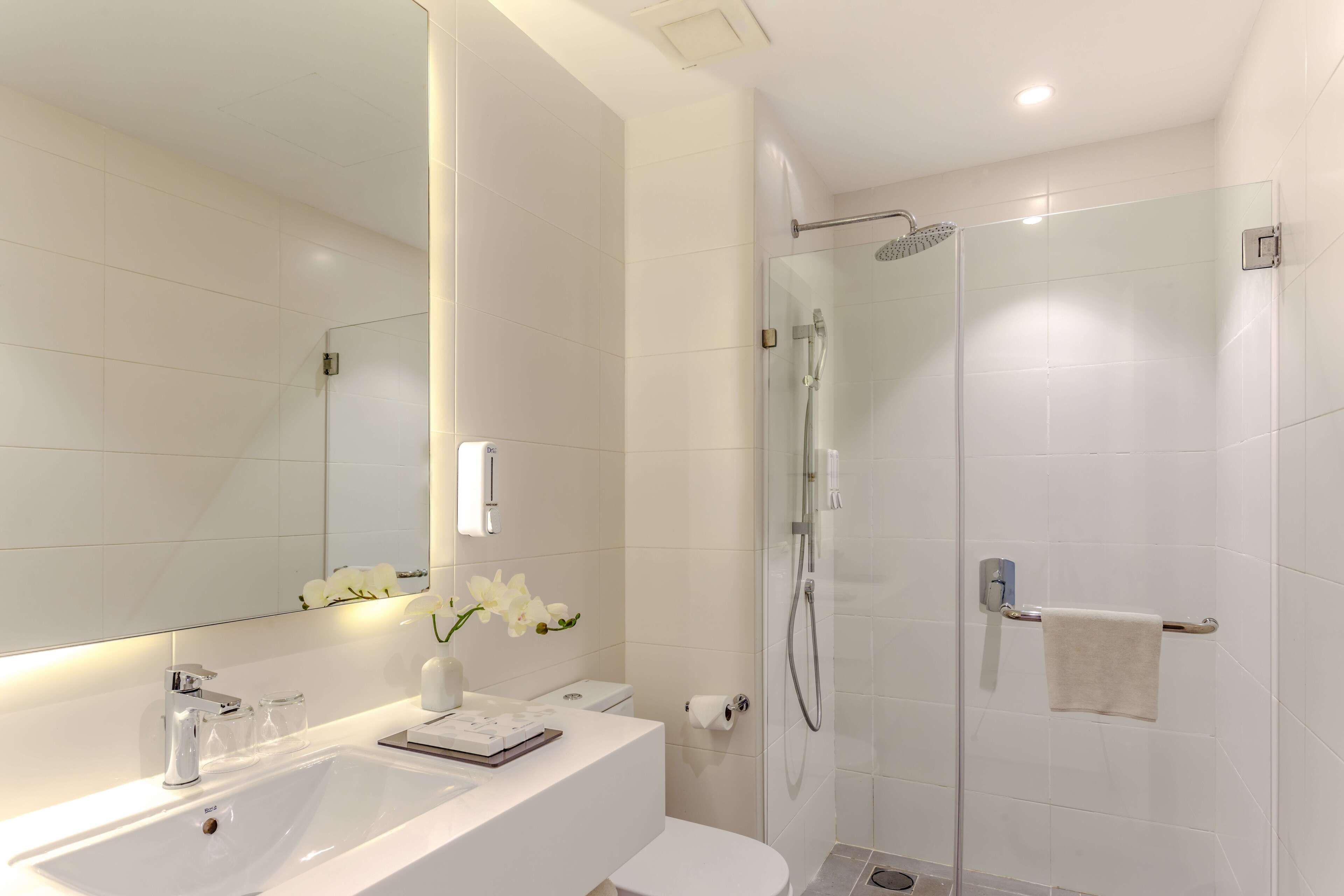 Une salle de bain moderne avec un lavabo blanc, un miroir et une douche en verre.