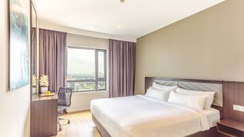 Una habitación de hotel moderna con una cama grande, un escritorio con una silla, una ventana con cortinas y vistas a la ciudad.