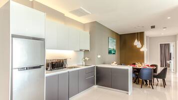 A modern kitchen with grey cabinets, a built-in oven, and a dining area with a table and chairs.