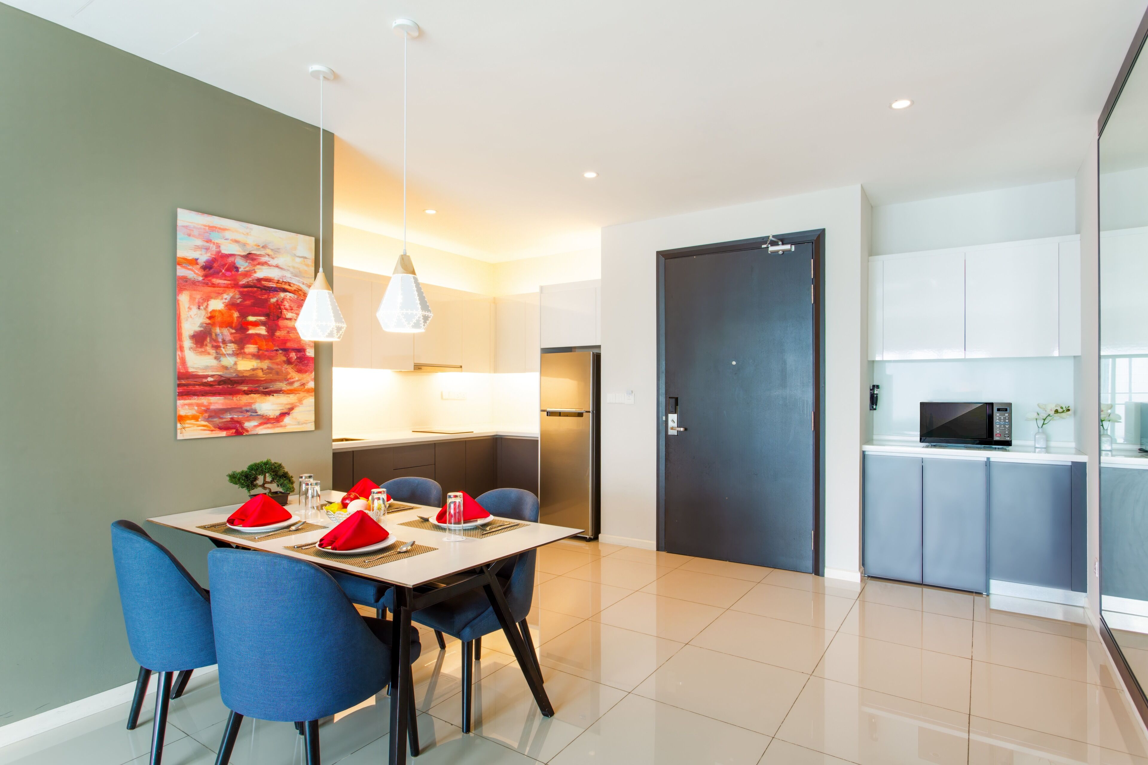 A modern dining area with a table set for four, blue chairs, and a red and white abstract painting on the wall.
