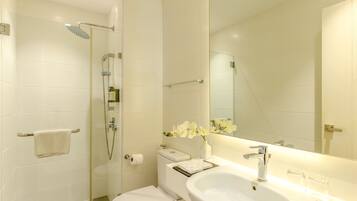 A modern bathroom with a glass-enclosed shower, a white toilet, and a large sink with a mirror above it.