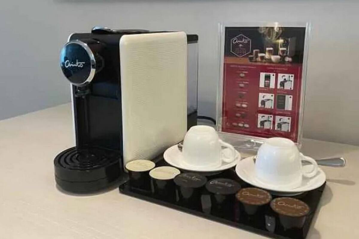 Eine Kaffeemaschine mit Kaffee-Kapselbehälter und zwei Tassen auf einer Ablagefläche.