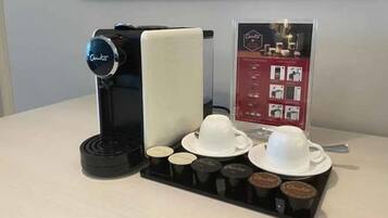 Une machine à café dotée d’un compartiment pour les capsules de café et de deux tasses posées sur un plateau.
