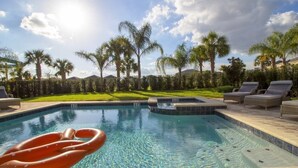 A swimming pool with lounge chairs and palm trees.