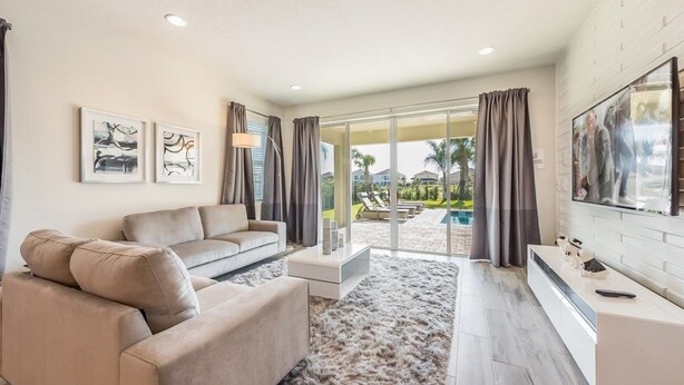 A modern living room with a beige sofa, a flat-screen TV, and artwork on the wall.