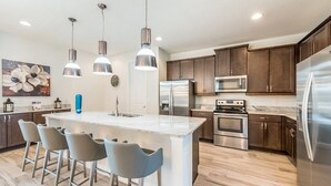 A modern kitchen with a central island, stainless steel appliances, and pendant lighting.