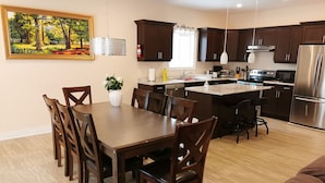Eine moderne Küche mit dunklen Holzschränken, einem Edelstahlkühlschrank und einem Essbereich mit Holztisch und -stühlen.