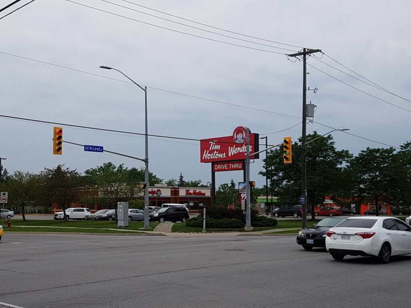 A Tim Hortons Wendy's drive-thru at a busy intersection with multiple lanes and traffic lights.