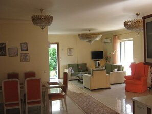 A living room with a dining area, a television, and a chandelier.