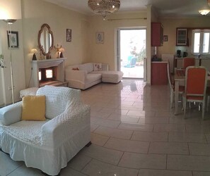 A spacious living area with a fireplace, a sofa, and a dining table with chairs.