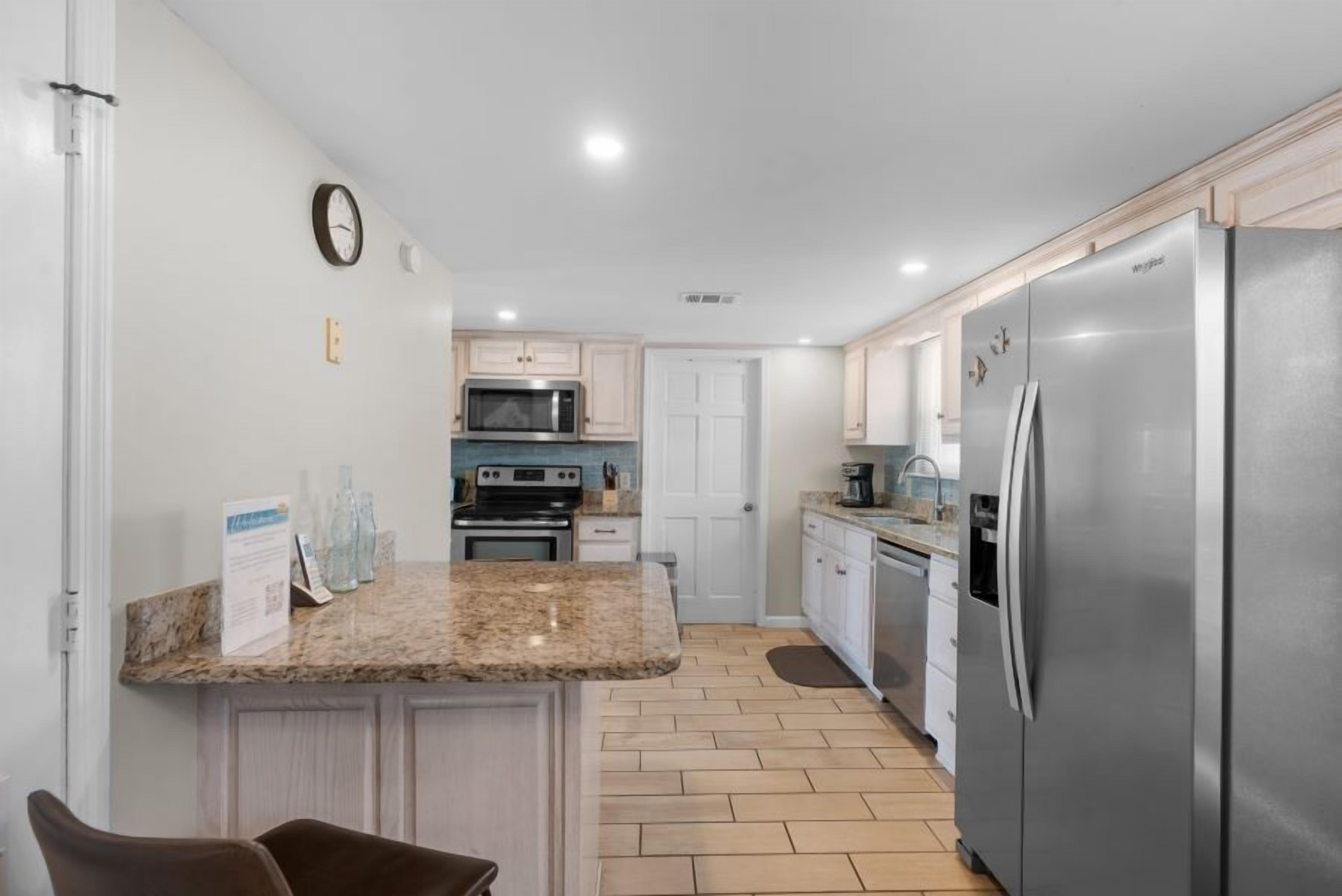 A modern kitchen with granite countertops, stainless steel appliances, and light wood cabinets.