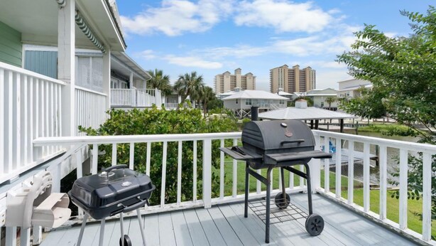 Un balcon avec un barbecue et une glacière, donnant sur une piscine et des immeubles.