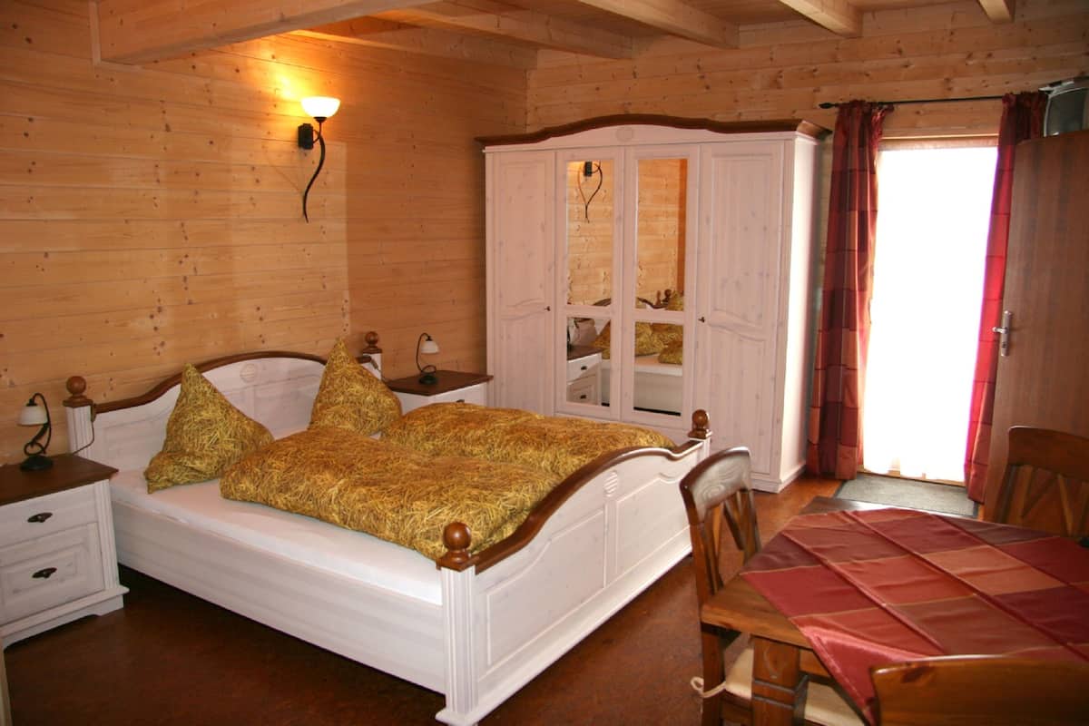 A wooden-paneled bedroom with a bed, a wardrobe, a table, and a chair.