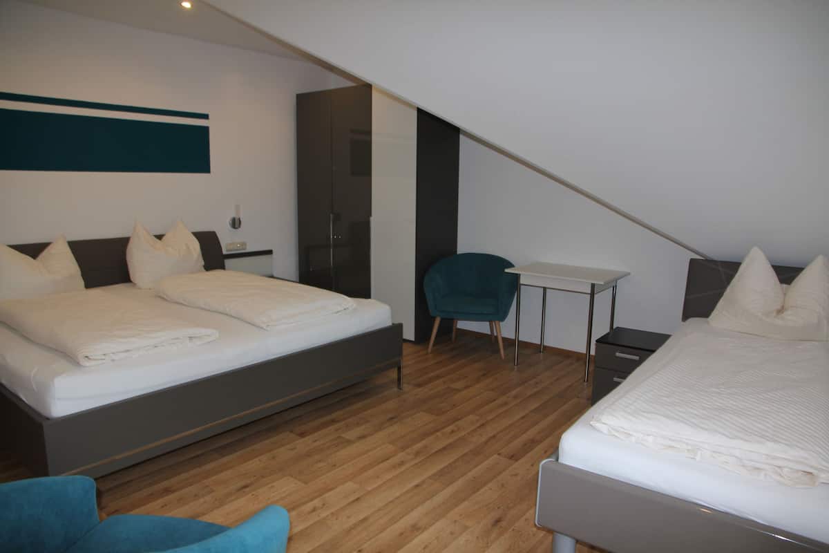 A modern bedroom with a large bed, a desk, and a chair.