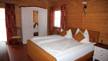 A wooden cabin bedroom with a bed, bedside table, and a chair.