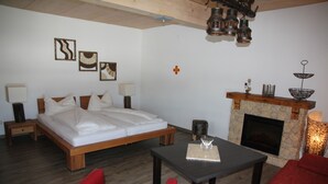 A bedroom with a bed, bedside tables, a fireplace, and a red chair.