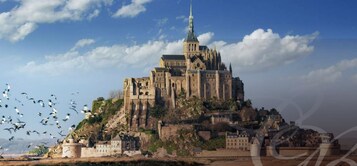 Un castillo histórico con una torre destacada, situado en una colina con edificios circundantes.