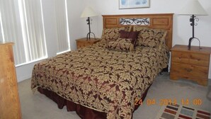 A bedroom with a large bed, two bedside tables, a nightstand, a window with blinds, and a framed picture on the wall. - Ahr237 - Hamlets at West Haven - 4 Bed 3 Baths Villa (Davenport)