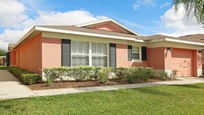 A single-story house with a red and beige exterior, a front porch, and a well-maintained lawn. - Smw148 - Sandy Ridge - 3 Bed 3 Baths Villa (Davenport)