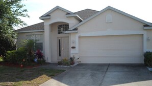 A single-story house with a garage, a front door, and a small garden with various plants.